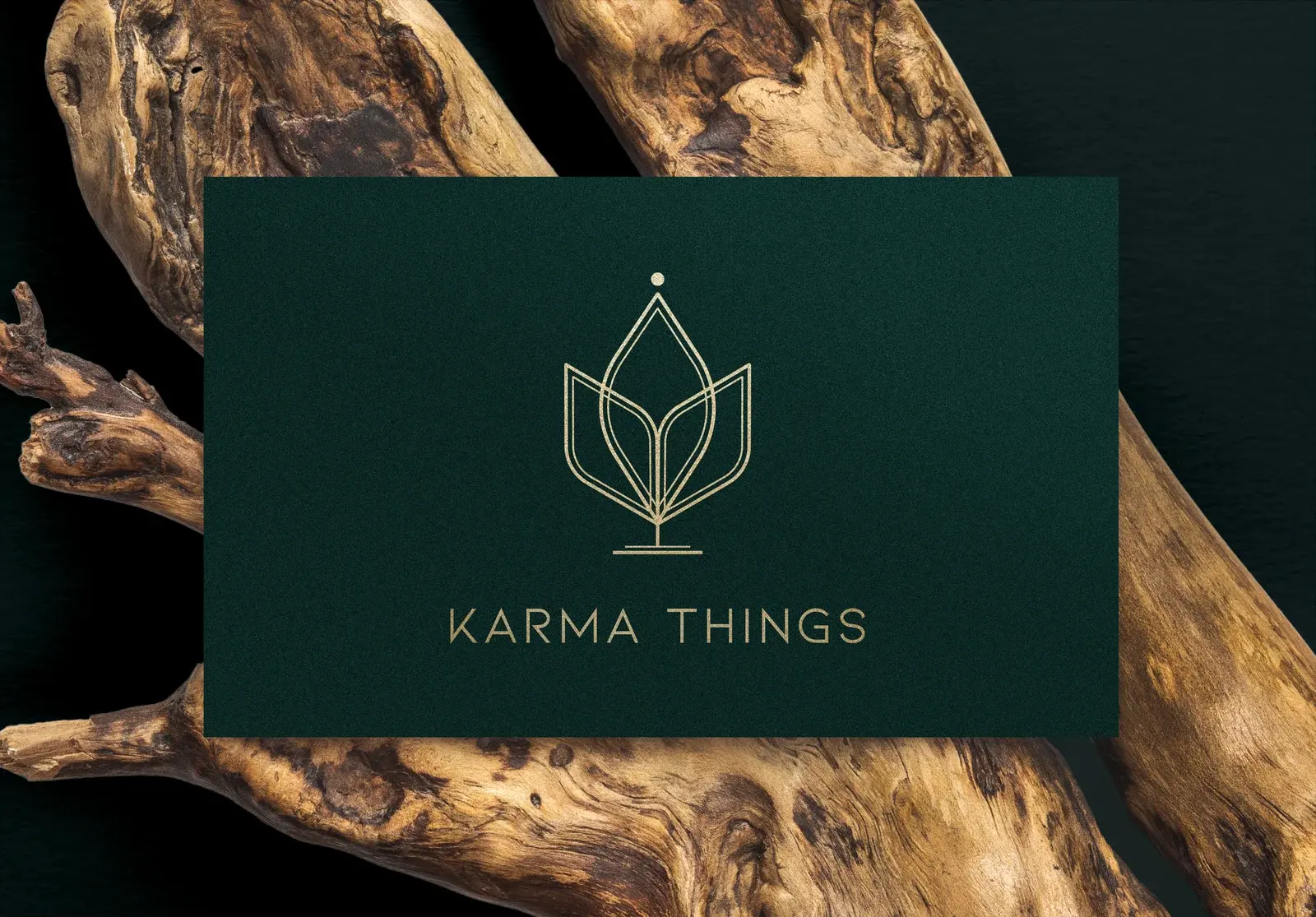 Forest-green Karma Things business card with a gold emblem on carved wood