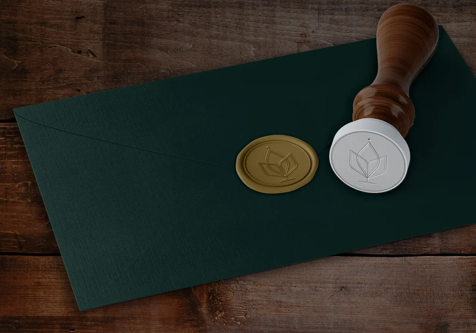 Gold and silver Karma Things wax seals beside a wooden stamp on a green envelope